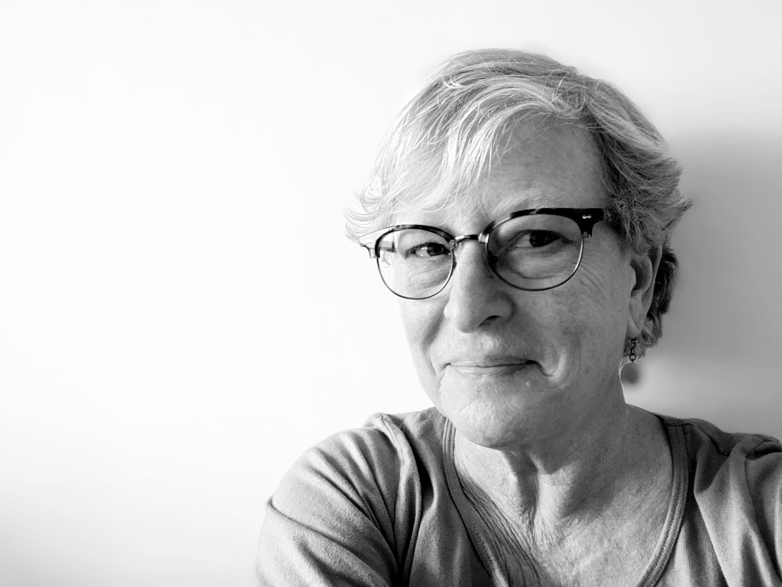 Head and shoulders of woman with short hair wearing glasses